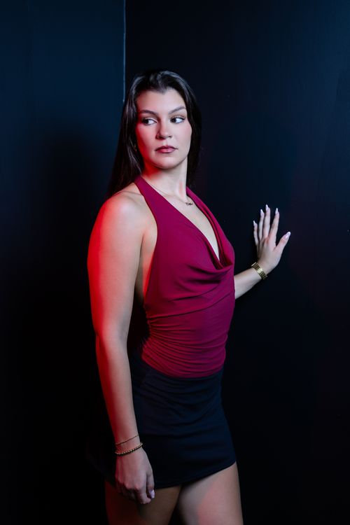 Free Woman in stylish red dress posing against a dark, moody background. Stock Photo