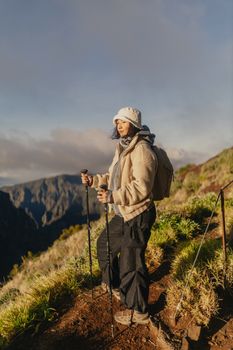 Woman hiking in Madeira, Portugal, capturing stunning mountain views at sunrise.