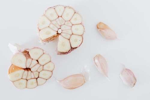 Free Top view of composition with garlic cut in half and pieces placed on white surface of table Stock Photo