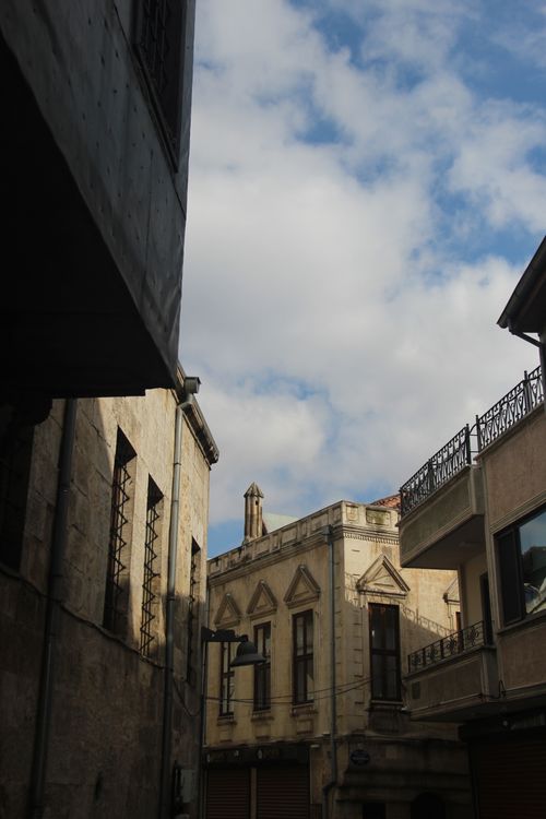 Free View of a historic urban alley with classic European architecture under a partly cloudy sky. Stock Photo
