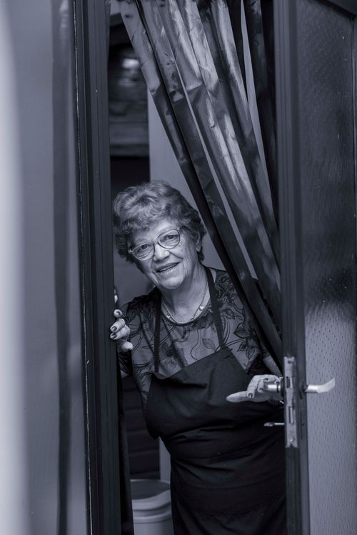 Free Charming senior woman smiling warmly from behind a doorway curtain. Stock Photo