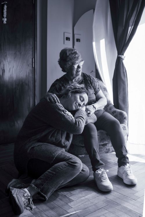 Free Touching scene of a woman resting her head on her elderly mother's knee, showcasing love and connection. Stock Photo