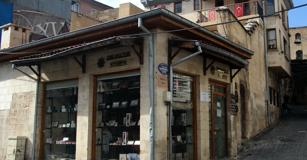 Charming stone building with a store, featuring Turkish flags, on a cobblestone street in Turkey.