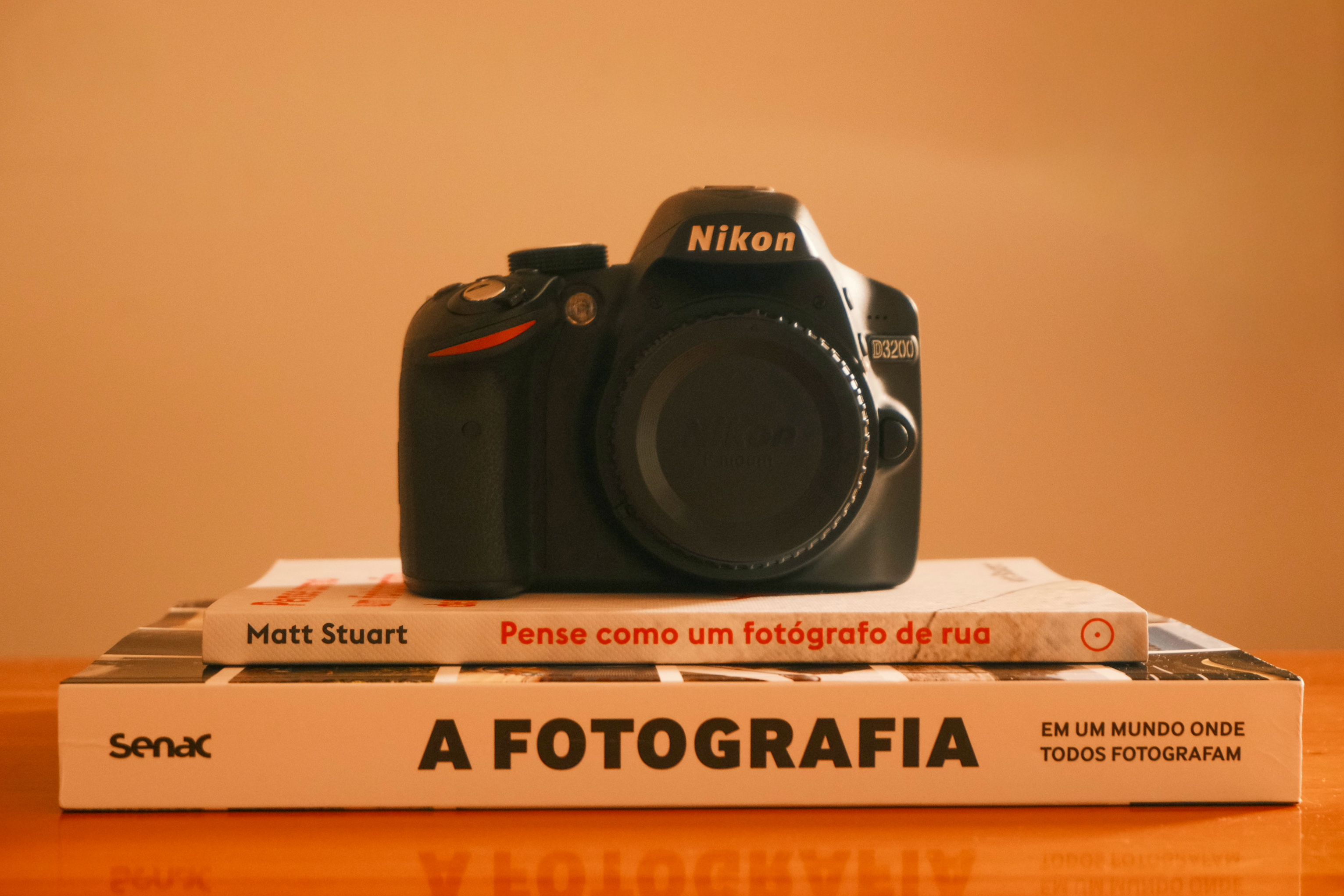 Nikon camera atop photography books by Matt Stuart, indoors, artistic shot.