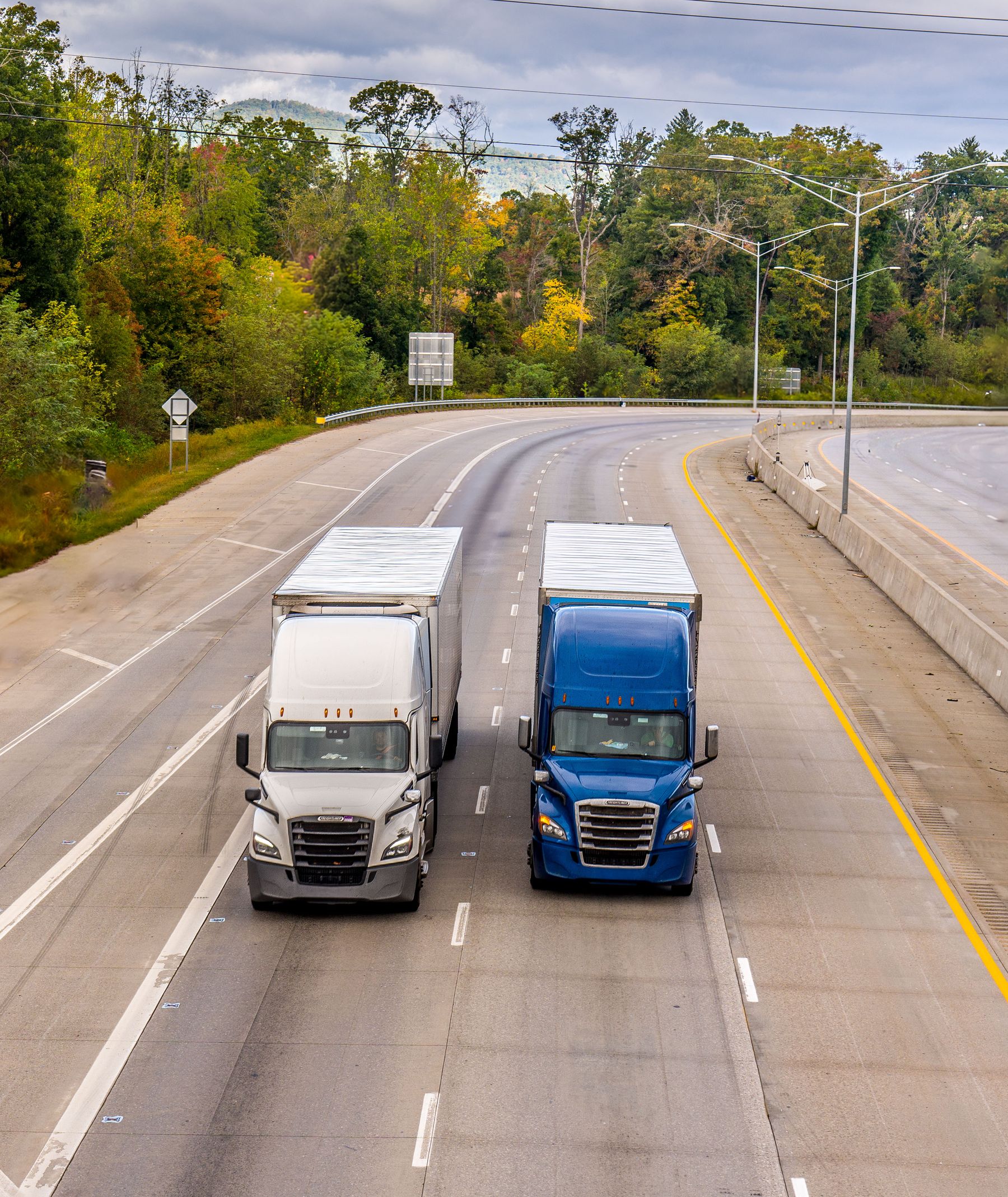 Two semi trucks driving side by side along a highway