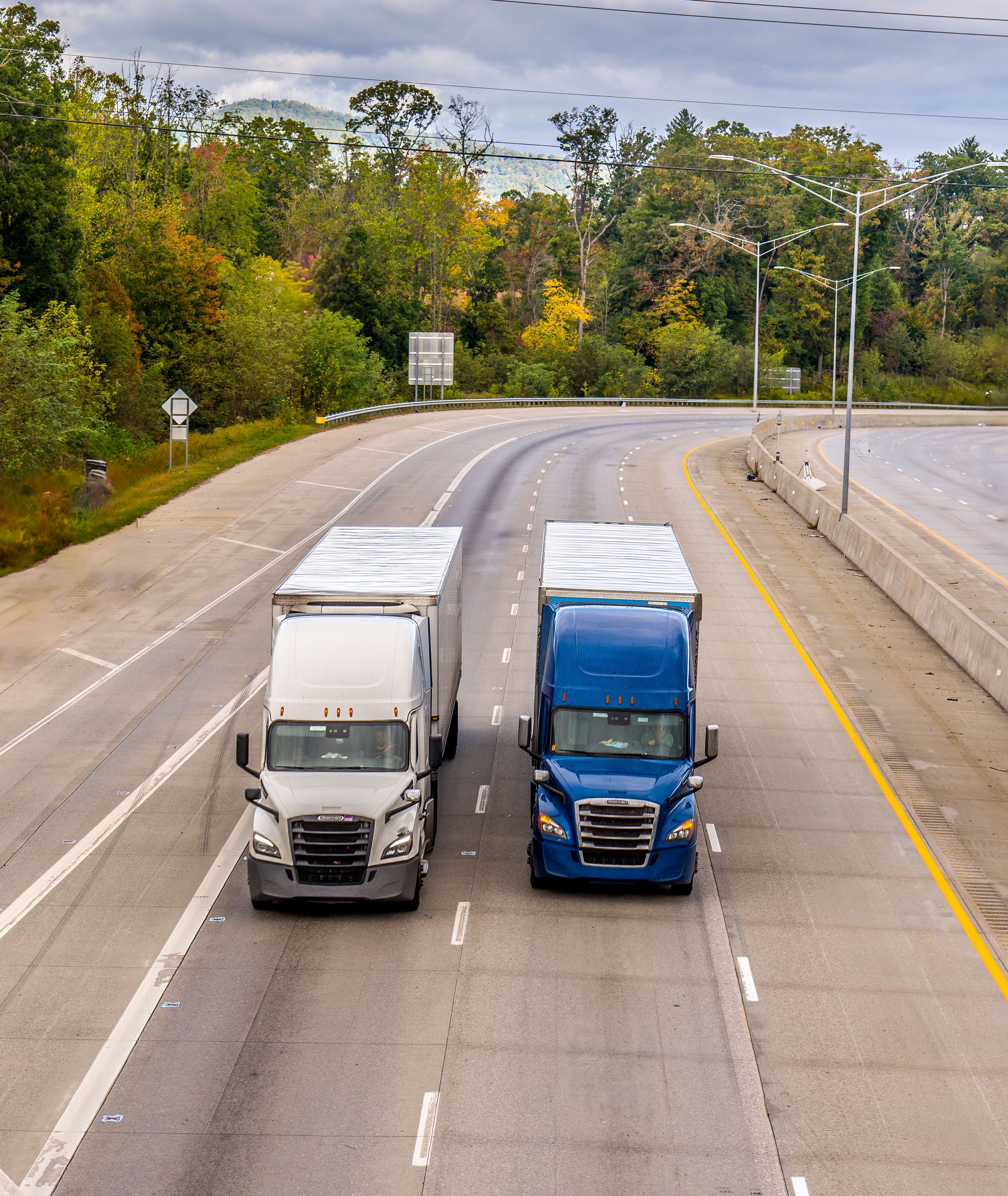 Freight Trucks Traveling on a Scenic Highway · Free Stock Photo