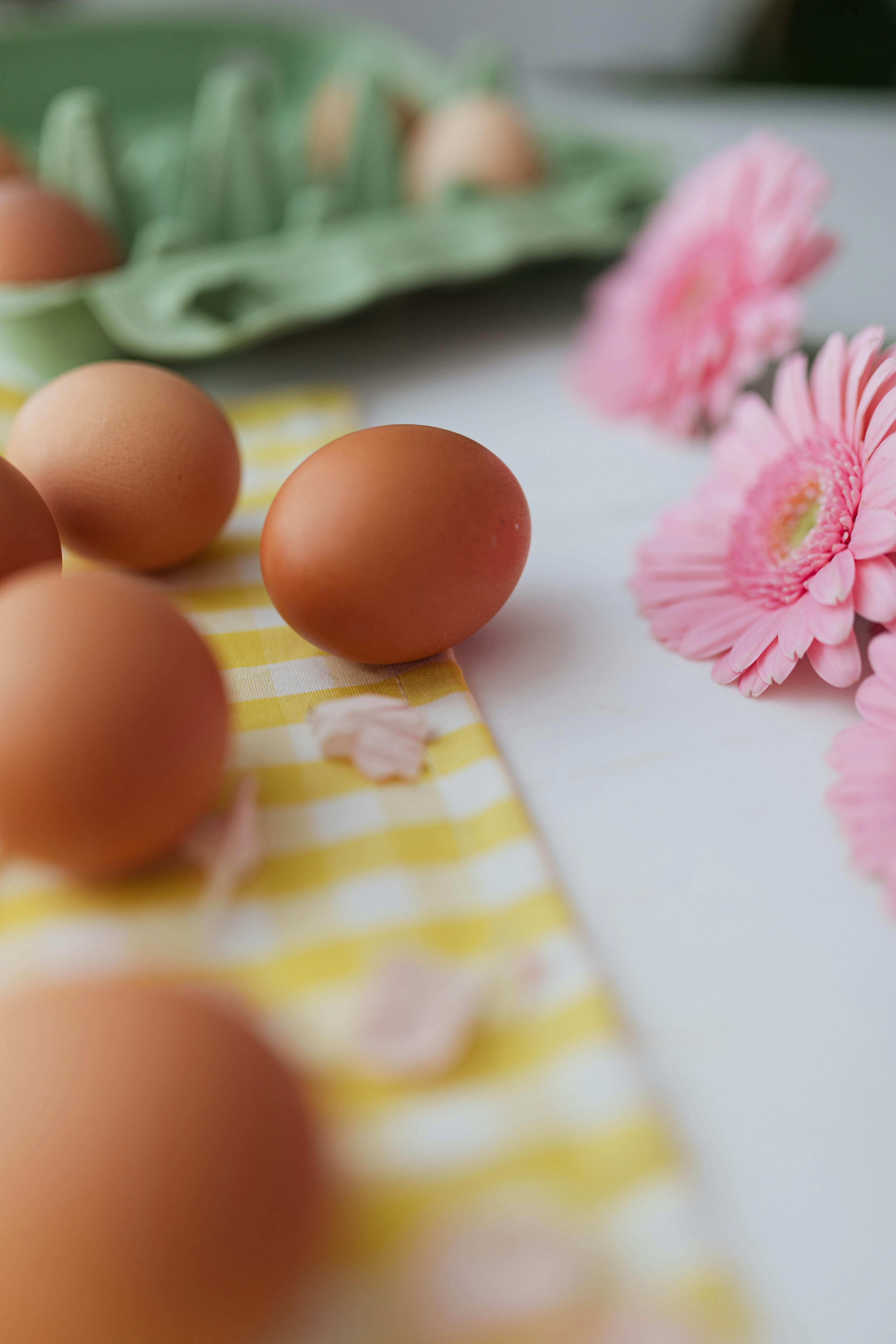 黄色格子布上，棕色鸡蛋与粉色花朵相映成趣，唤起了清新的春日气息