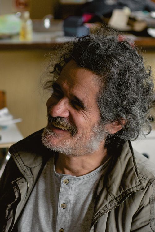 Free A senior man with curly hair and beard smiling warmly indoors. Stock Photo
