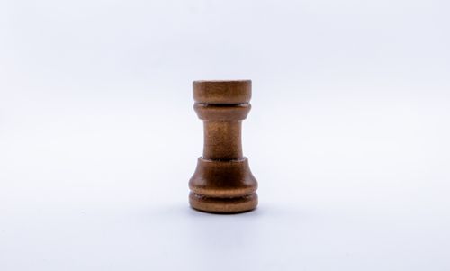 Free A wooden chess rook piece standing upright on a plain white background, showcasing minimalist design. Stock Photo