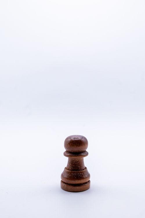 Free A single wooden chess pawn on a white background, perfect for strategy and game-related themes. Stock Photo