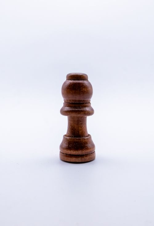 Free A wooden chess bishop piece isolated against a plain white backdrop, ideal for strategy themes. Stock Photo