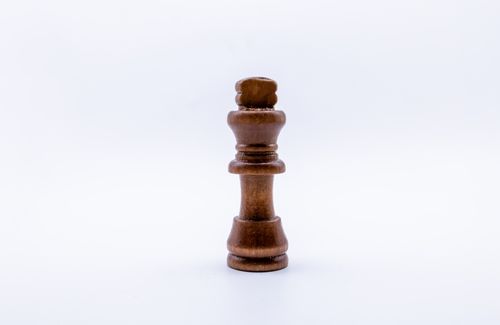 Free A single wooden chess king piece standing upright on a plain white background, isolated view. Stock Photo