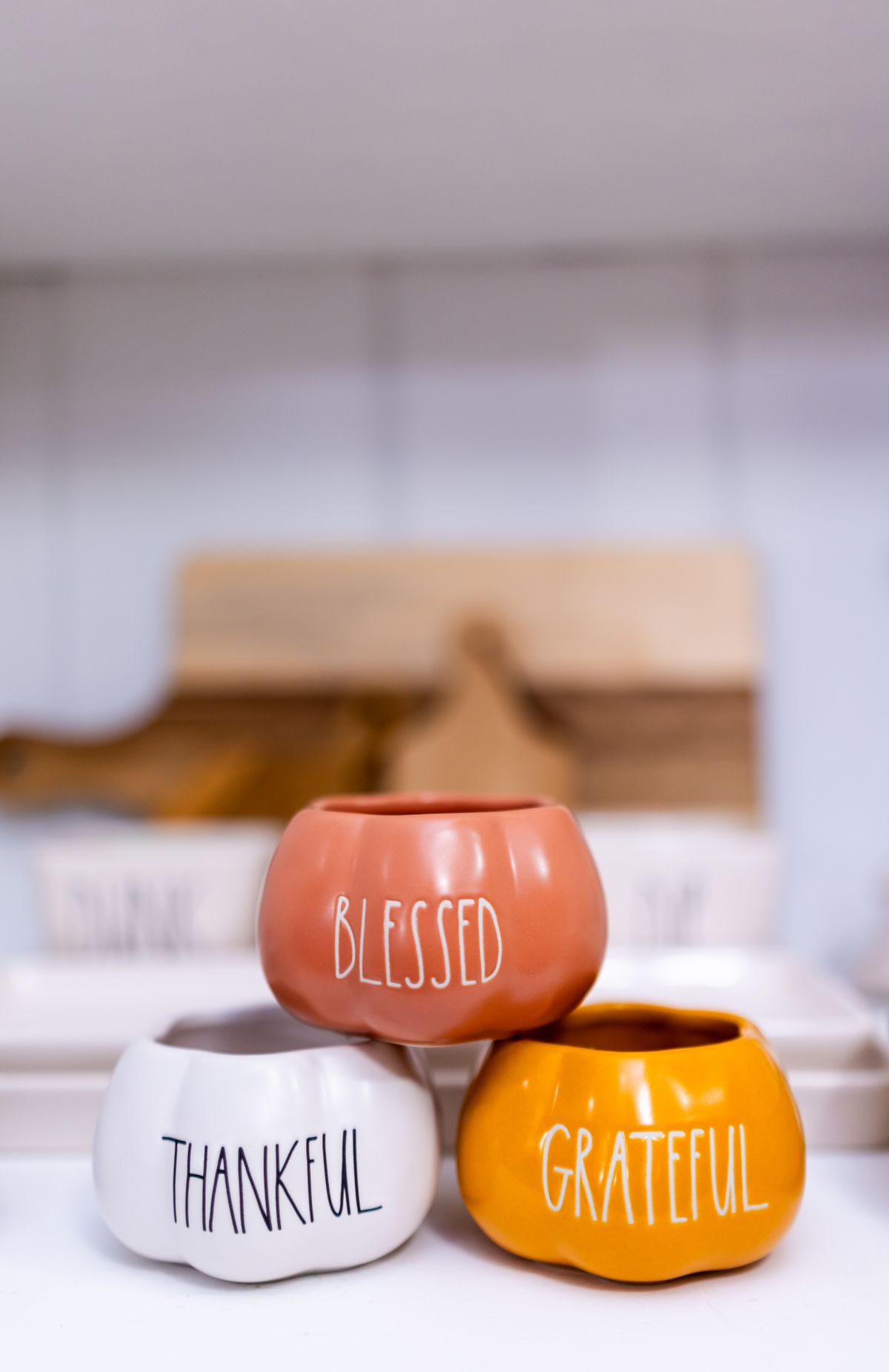 Three pottery pumpkins with 'Blessed,' 'Thankful,' and 'Grateful' text for Thanksgiving decor. Stock Photo.