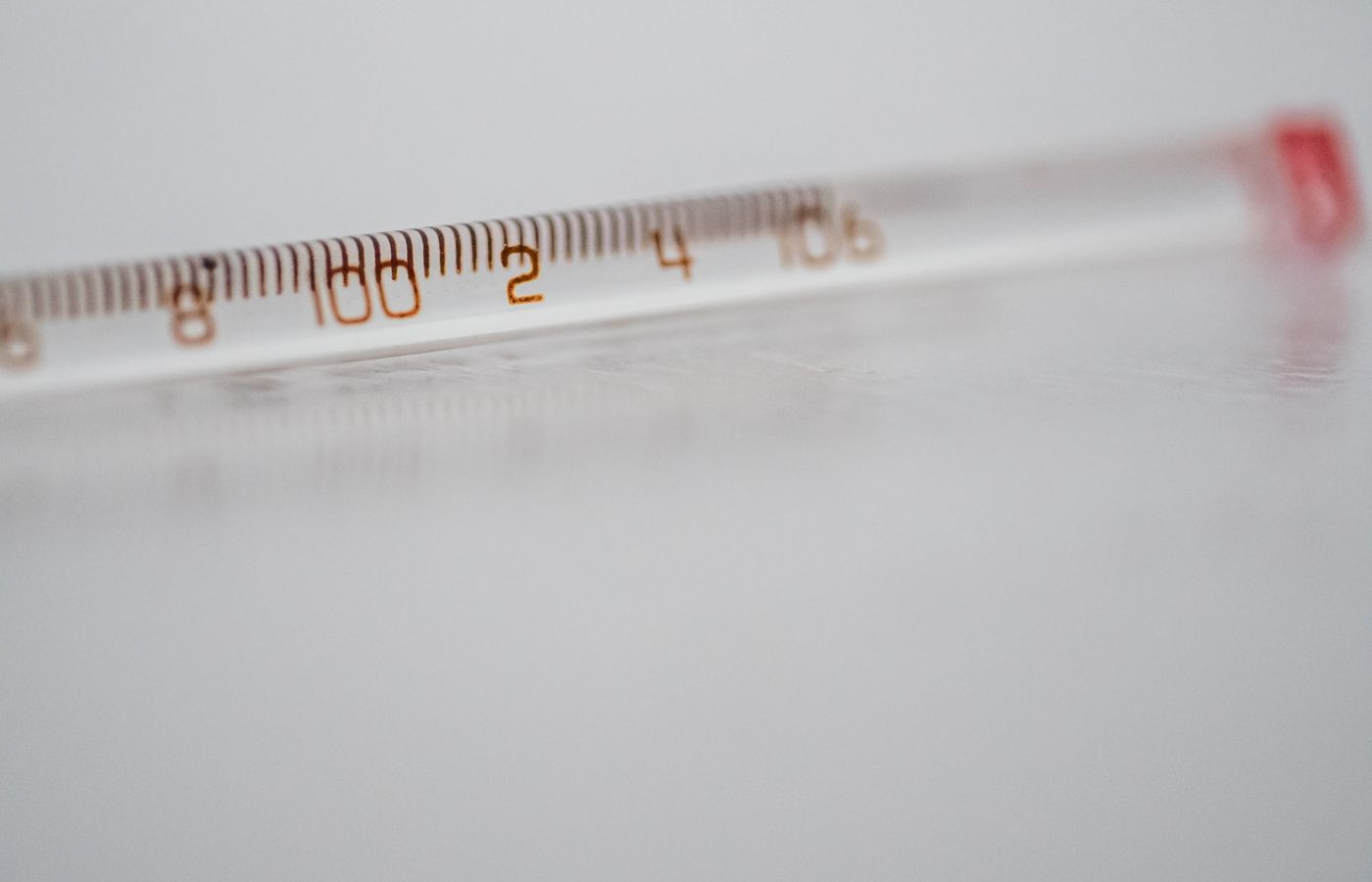 Detailed close-up of a mercury glass thermometer on a white surface, showing temperature measurements.