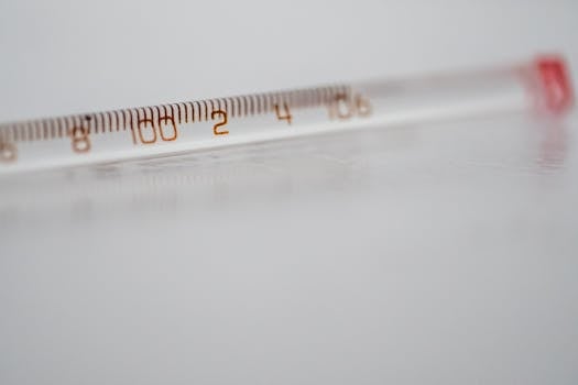 Detailed close-up of a mercury glass thermometer on a white surface, showing temperature measurements.