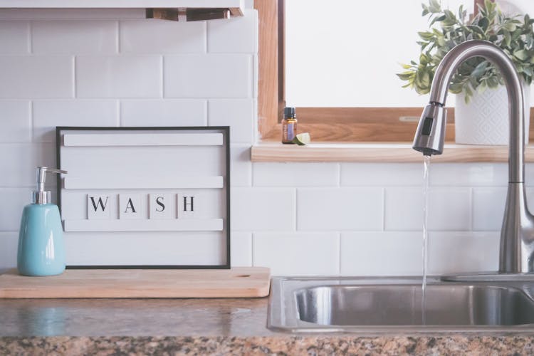 Faucet With Water And Soap In Bathroom With WASH Inscription