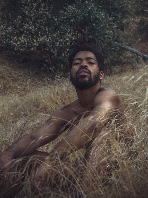 Topless Man Sitting On Brown Grass Field