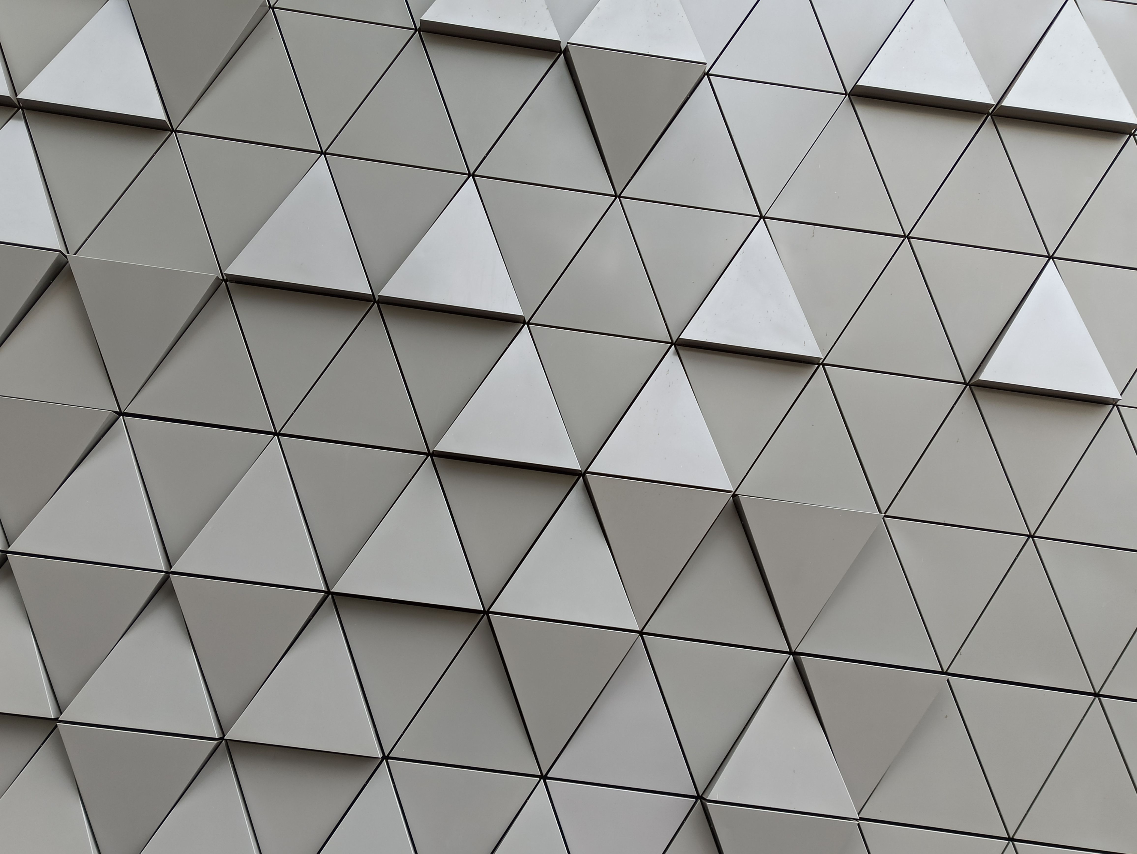Abstract view of a modern wall with triangular geometry and a metallic finish.