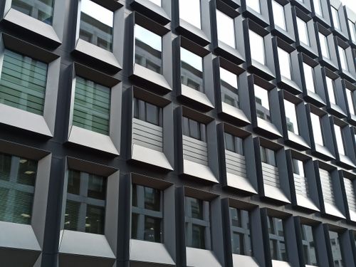 Free Contemporary office building facade with repeating geometric patterns in urban setting. Stock Photo
