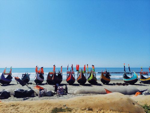 Free Colorful traditional boats lined up on the sandy shores of Cox's Bazar under a bright blue sky. Stock Photo
