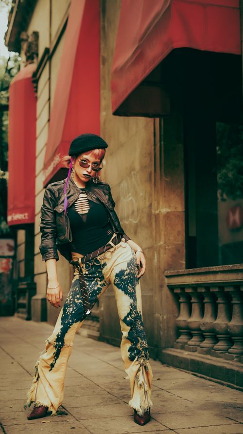 Free Stylish woman in edgy outfit poses on city street under red awnings. Stock Photo