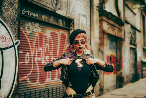 Free Young woman in edgy fashion stands in a graffiti-covered alley, exuding confidence and style. Stock Photo