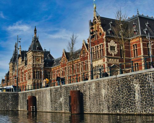 Free Beautiful architectural view of Amsterdam Central Station along the canal on a clear day. Stock Photo