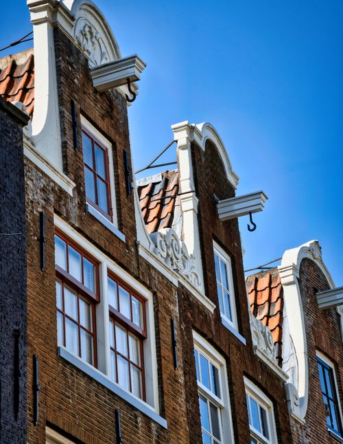 Free Classic Dutch gabled houses against a bright blue sky in Amsterdam, Netherlands. Stock Photo