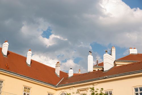 Free A charming view of historic European rooftops against a dramatic cloudy sky. Stock Photo
