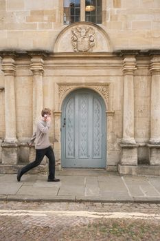 A person walking past a historic building in Oxford, England, showcasing traditional architecture.