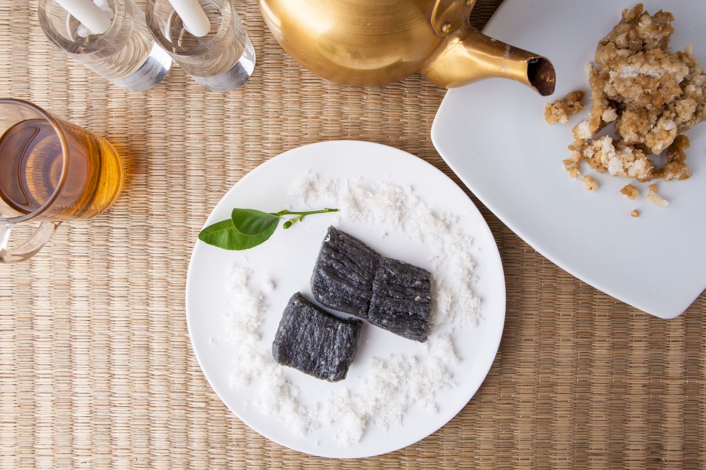 Asian sweets served on a white plate with tea and decorative elements, showcasing a minimalist food presentation.