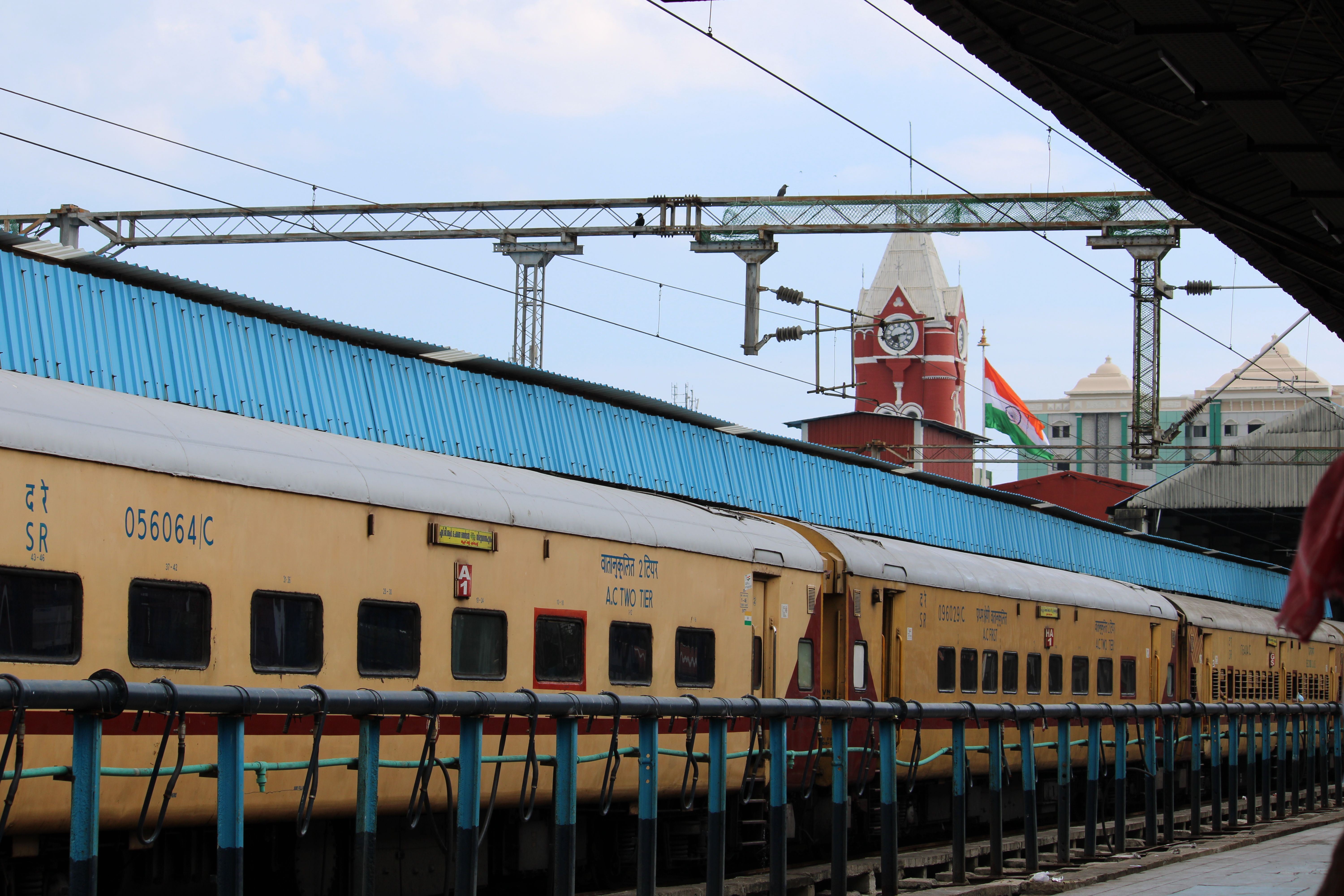 A vibrant scene of Chennai Central Railway Station with an Indian train and the national flag.