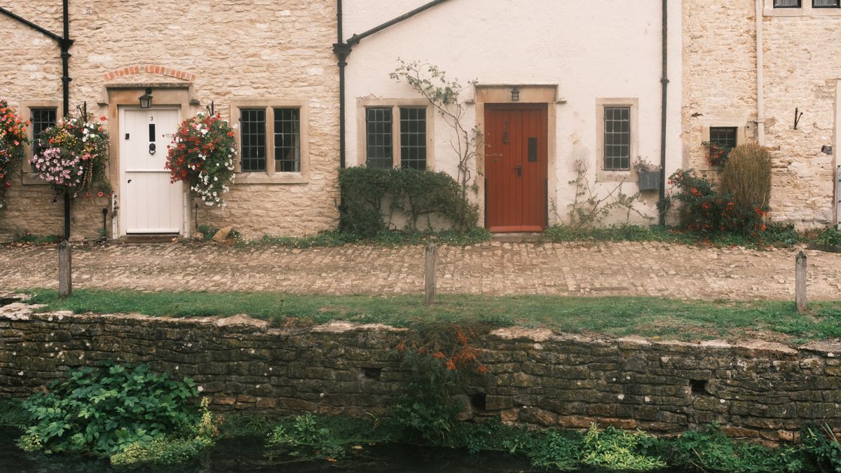 Stone cottages behind a low wall and a stream in Castle Combe, Wiltshire