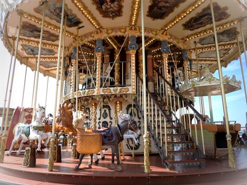 Free A classic carousel with ornate horses and lion figures under a sunny sky. Stock Photo