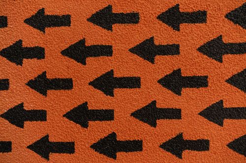 Free Abstract pattern with black arrows pointing left on a textured orange background. Stock Photo
