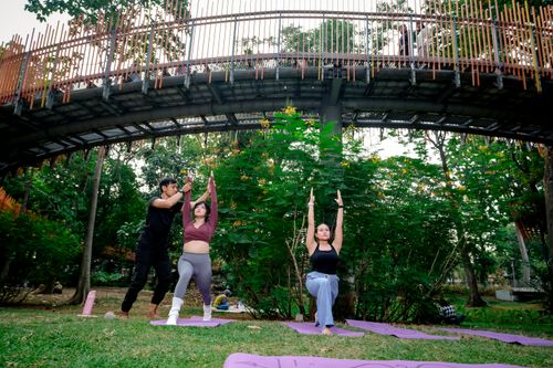 Free Yoga class in Jakarta with personal trainer amidst urban greenery and modern architecture. Stock Photo