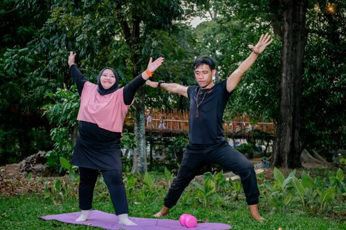 Free Two adults practicing yoga in a lush urban park in Jakarta, fostering wellness and mindfulness. Stock Photo