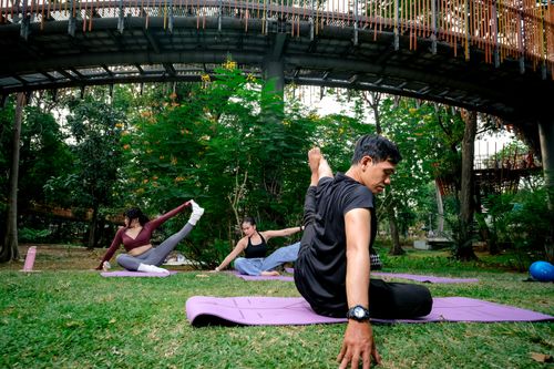 Free Group exercise in Jakarta park featuring yoga poses under pedestrian bridge. Stock Photo
