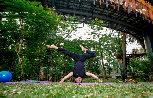 Free A woman practicing yoga upside down in a tropical urban park in Jakarta, Indonesia. Stock Photo
