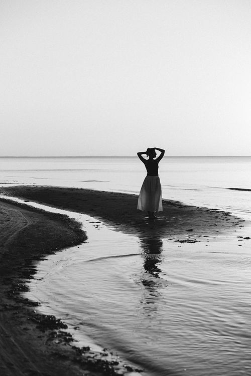 Free Silhouette of a woman on Tallinn's beach at twilight, captured in monochrome. Stock Photo