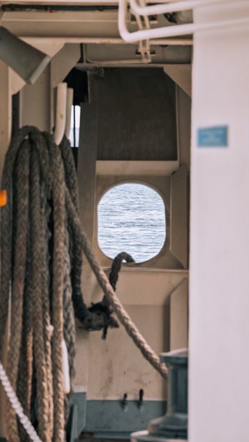 Free A nautical scene featuring ropes and an ocean view through a ship porthole. Stock Photo