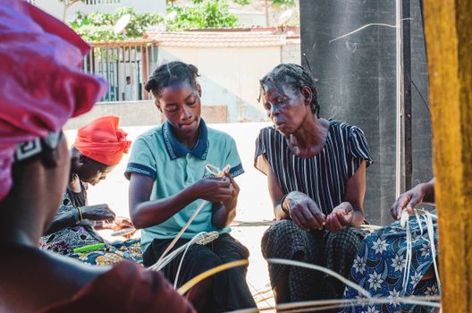 Group of women engaged in traditional basket weaving in an outdoor setting. Authentic cultural craftsmanship.
