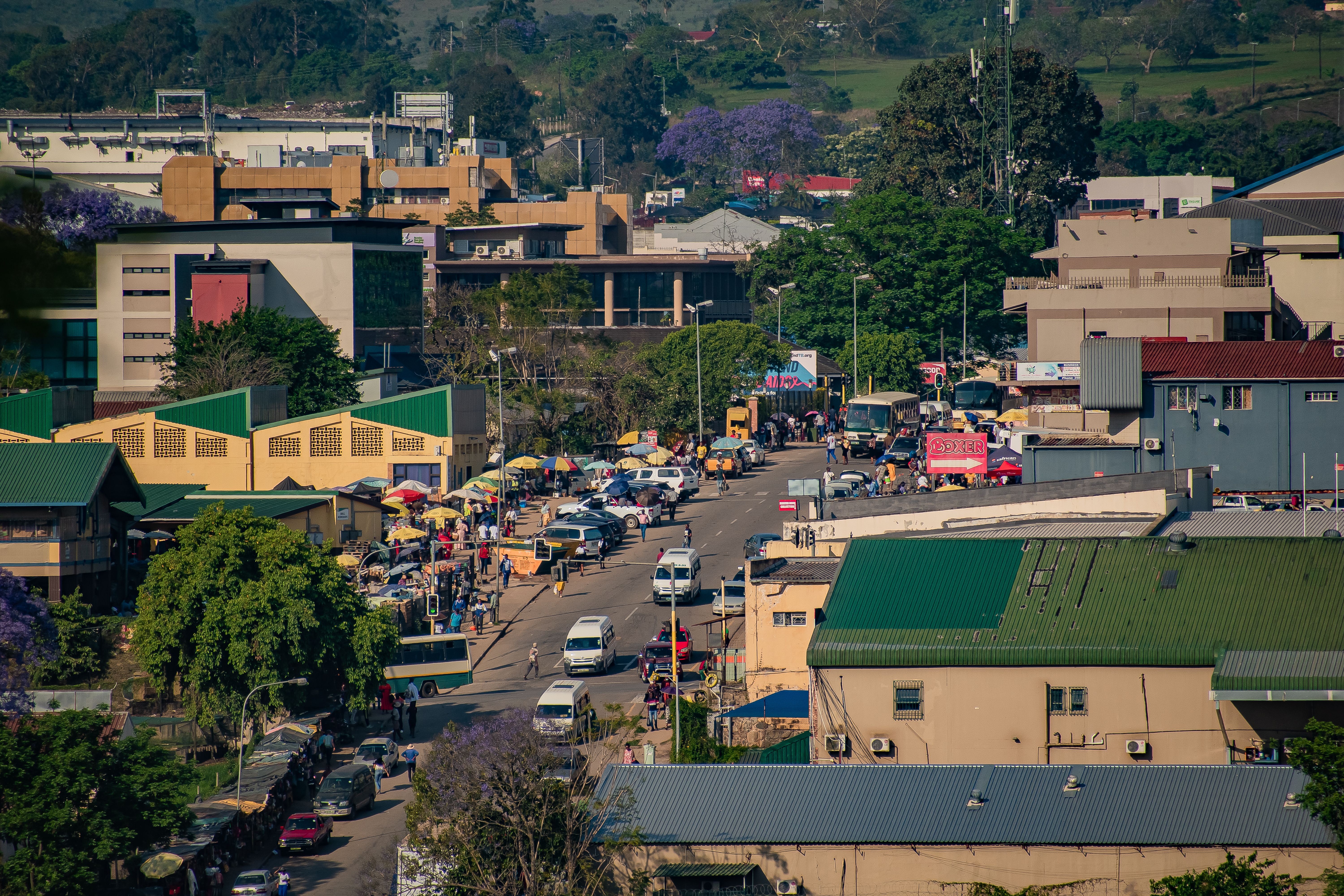A vibrant, busy street scene in Eswatini's urban center with colorful jacaranda trees.