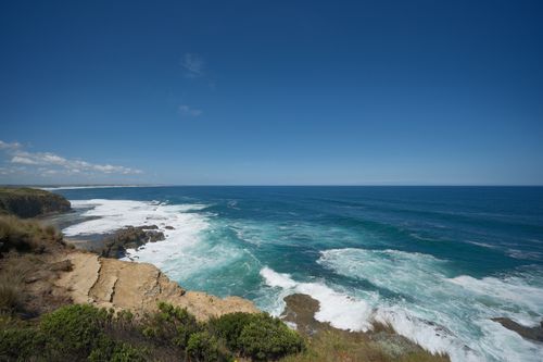 Free Stunning view of an ocean coastline with clear blue skies and crashing waves. Stock Photo