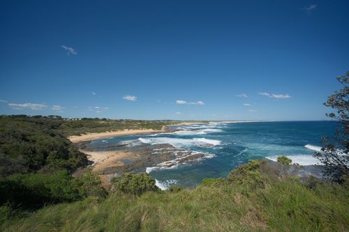 Free Explore a breathtaking coastal scene with rolling waves, rocky shoreline, and vibrant blue sky. Stock Photo