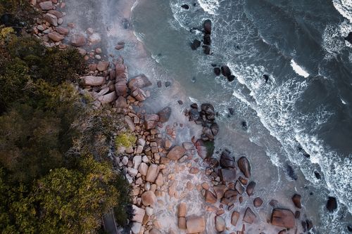 Free Aerial perspective of a rocky shore meeting the ocean waves. Stock Photo
