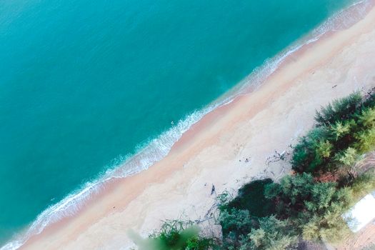 An aerial image capturing a pristine tropical beach with turquoise waters and lush greenery.