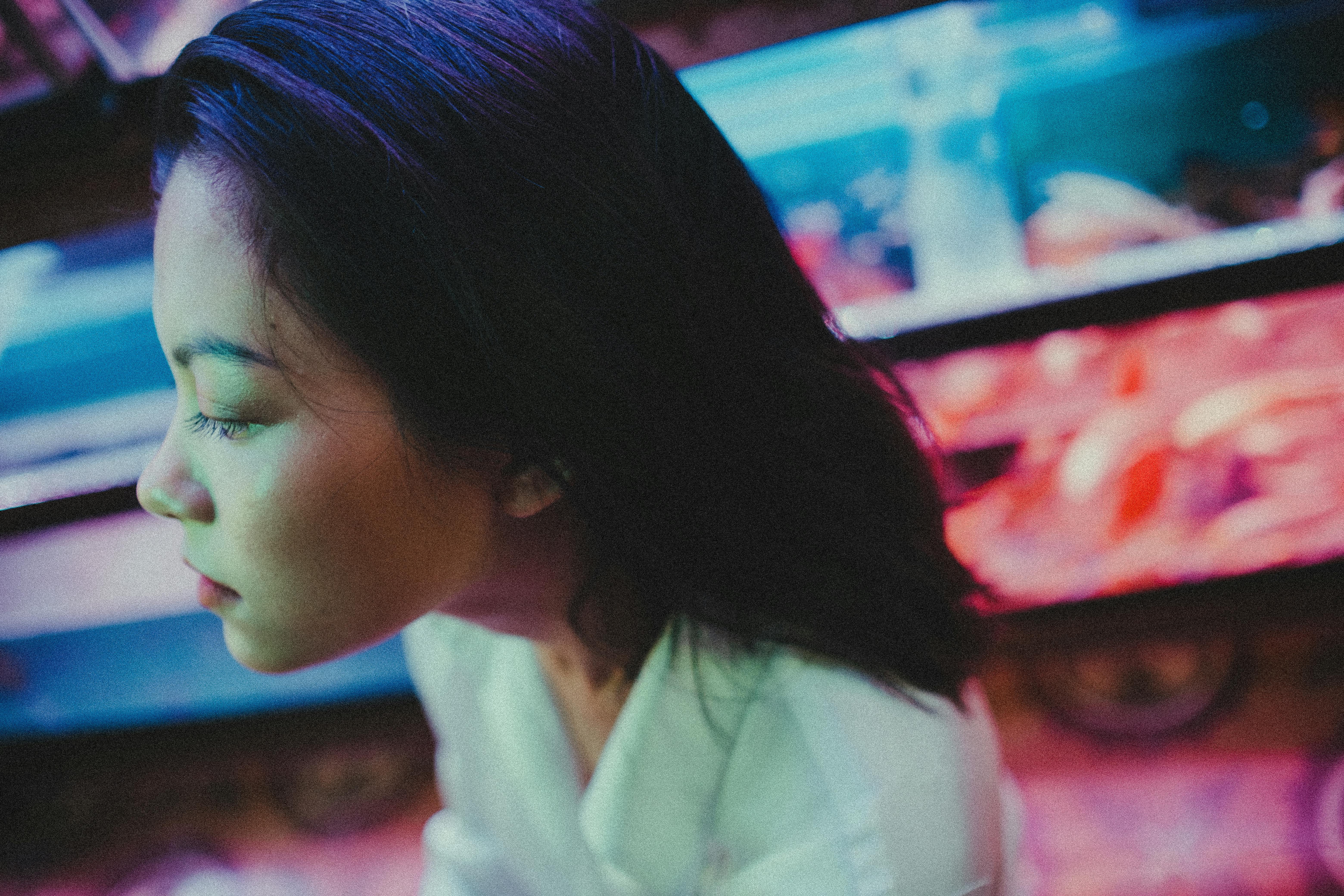 From above young Asian female with closed eyes while standing on blurred background of fish tanks