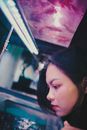 Young ethnic female watching fish in water tank while visiting modern pet store