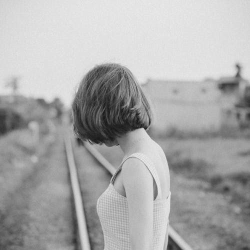 Anonymous woman on railway under sky in rural zone